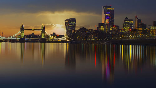 Scenic view of river by illuminated buildings against sky at night