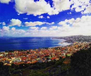 Scenic view of sea and cityscape against cloudy sky