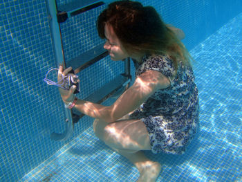 Young woman with technology in swimming pool