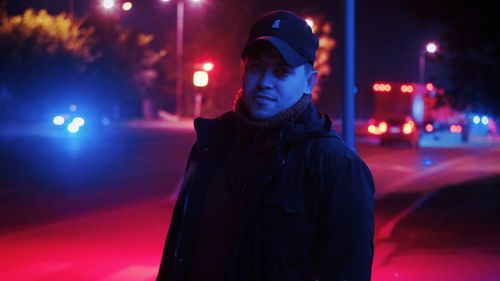 Portrait of man standing on illuminated street at night