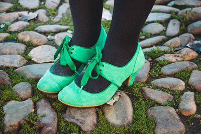 Low section of woman wearing green shoes standing on rock