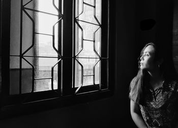 Woman looking through window at home