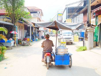 Rear view of man walking on street against buildings