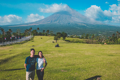 Portrait of young couple on field against sky