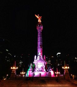 Statue in illuminated city at night