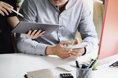 Midsection of man using mobile phone on table