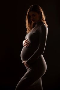 Young woman standing against black background