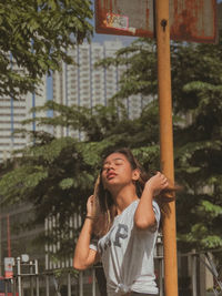 Portrait of young woman standing against trees