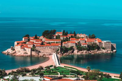 Buildings by sea against blue sky