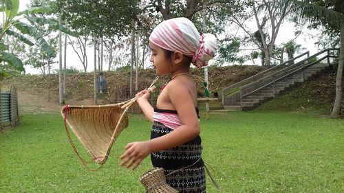 Side view of girl wearing hat standing against plants