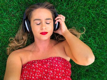 High angle view of woman enjoying music while lying down on grass