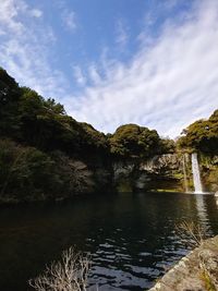 Scenic view of rocks by trees against sky