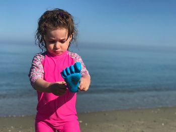 Girl holding toy while standing at beach