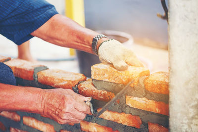 Cropped image of manual worker making brick wall at construction site