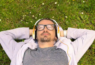 High angle view of man day dreaming while relaxing on grass with hands behind head.