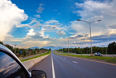 Cars on highway against cloudy sky