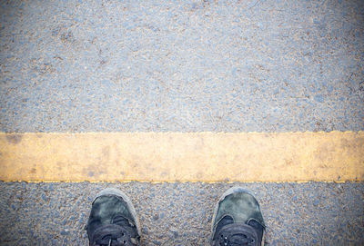 Male feet and old black shoes standing on the concrete floor or street asphalt pavement