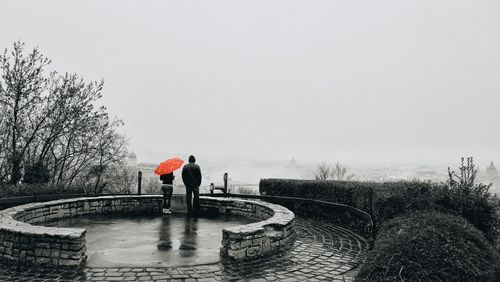 Man standing on riverbank against clear sky