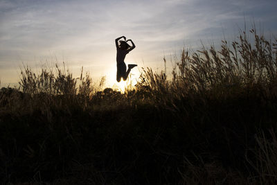 Silhouette man standing on field against sky during sunset