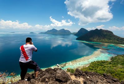 Rear view of man looking at mountains against sky