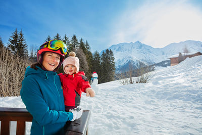 Portrait of smiling woman standing on snowcapped mountain