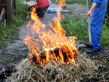 Low section of man standing by fire on field