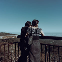 Rear view of woman looking at sea against clear sky