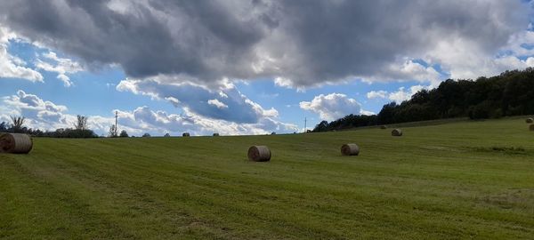 Hay bales on field against sky