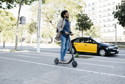 Man with backpack riding his e-scooter on a bicycle lane