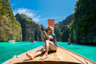 Male tourist taking pictures at the prow of a long-tail boat on a tropical island, koh lipe,  sea, 