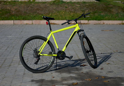 A yellow bicycle stands in the middle of the street on an autumn day