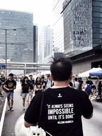 Rear view of people standing on street against buildings