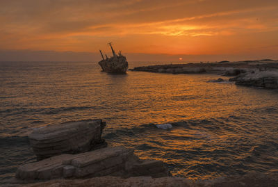 Scenic view of shipwreck against sky during sunset