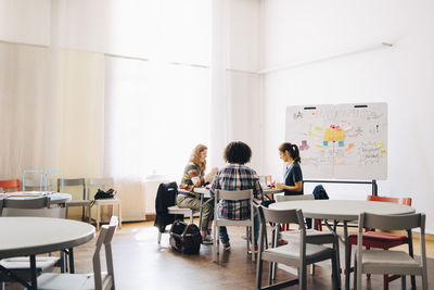 Team of multi-ethnic engineers working at table by whiteboard in creative office