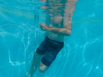 Low section of man swimming in pool