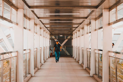 Rear view of man walking in corridor of building