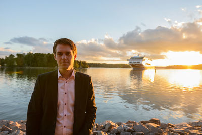 Portrait of young man standing in lake against sky