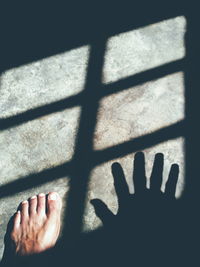 Low section of man standing on floor with shadows