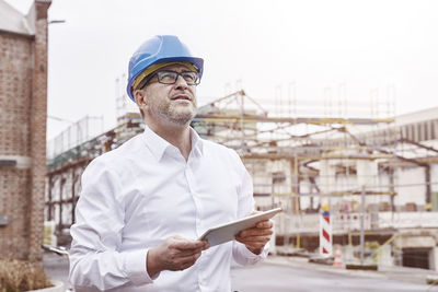 Portrait of smiling man with tablet wearing blue hart hat