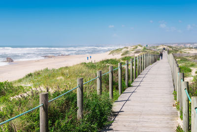 Footpath leading towards sea against sky