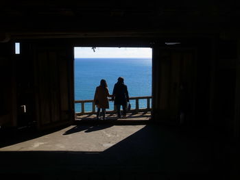 Silhouette people standing by sea against sky