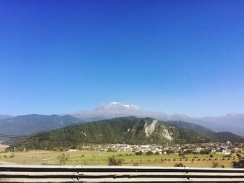 Scenic view of landscape and mountains against clear blue sky