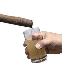 Close-up of hand holding drink against white background