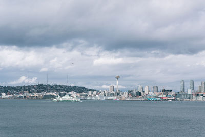 Sea by cityscape against sky