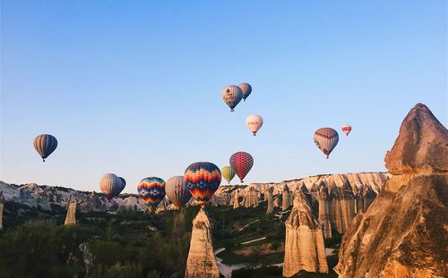 Hot air balloons flying over rocks against sky