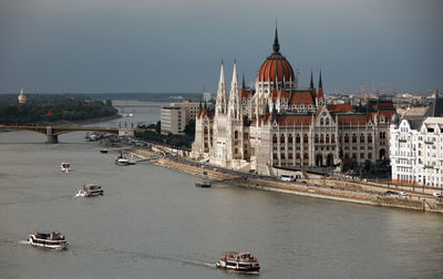 Boats in river by hungarian parliament building in city