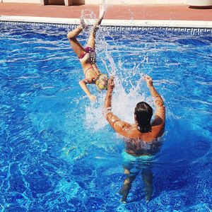 Girl jumping with father in swimming pool