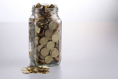 Close-up of coins in jar against white background