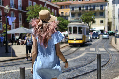 Rear view of young woman walking on street in city