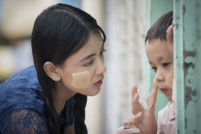 Woman applying cream on face of boy